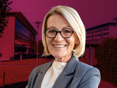 Ältere Schulleiterin mit Schulgebäude im Hintergrund